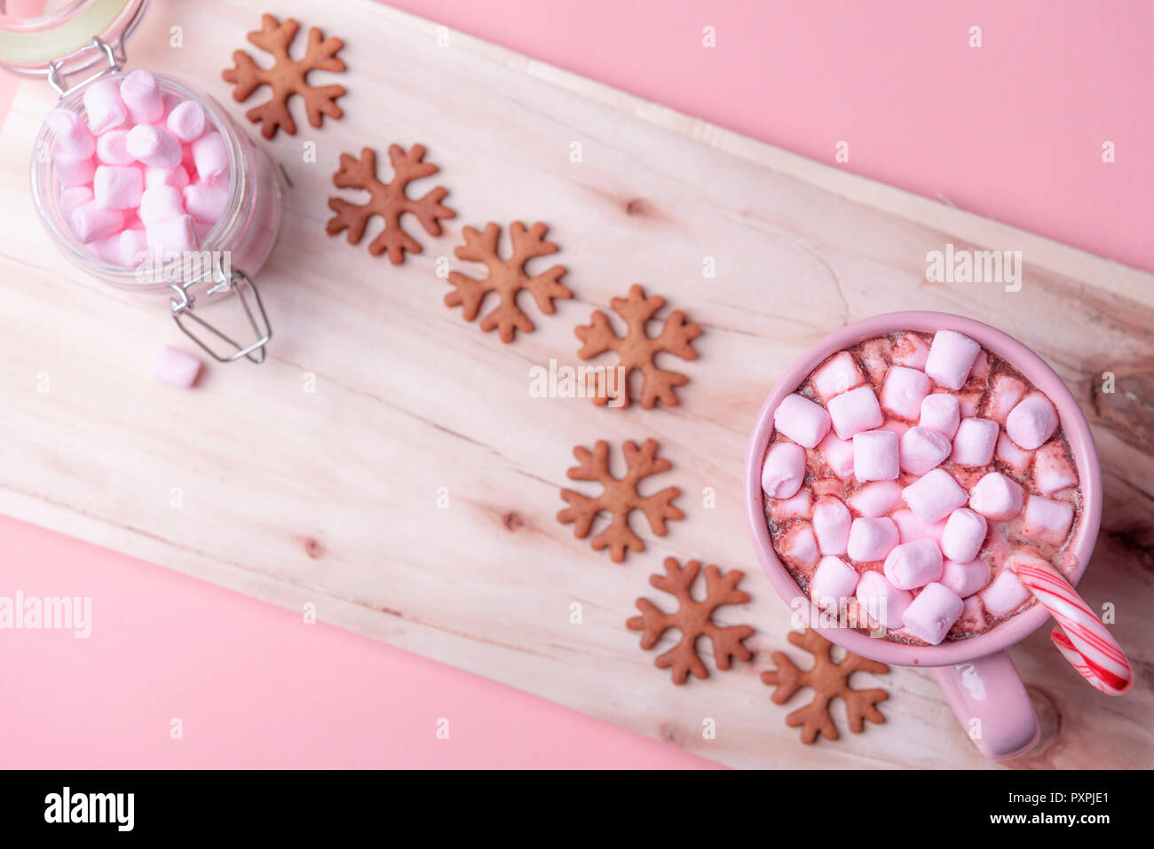 American winter sweets, a cup of hot chocolate with mini marshmallows, a candy cane and gingerbread cookies in snowflakes shape, on a wooden platter. Stock Photo