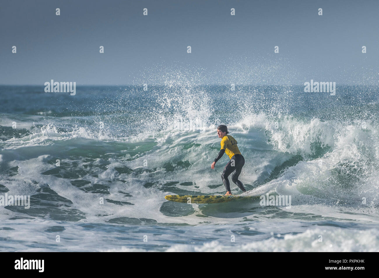 A surfer competing in a longboard surfing competition at Fistral in