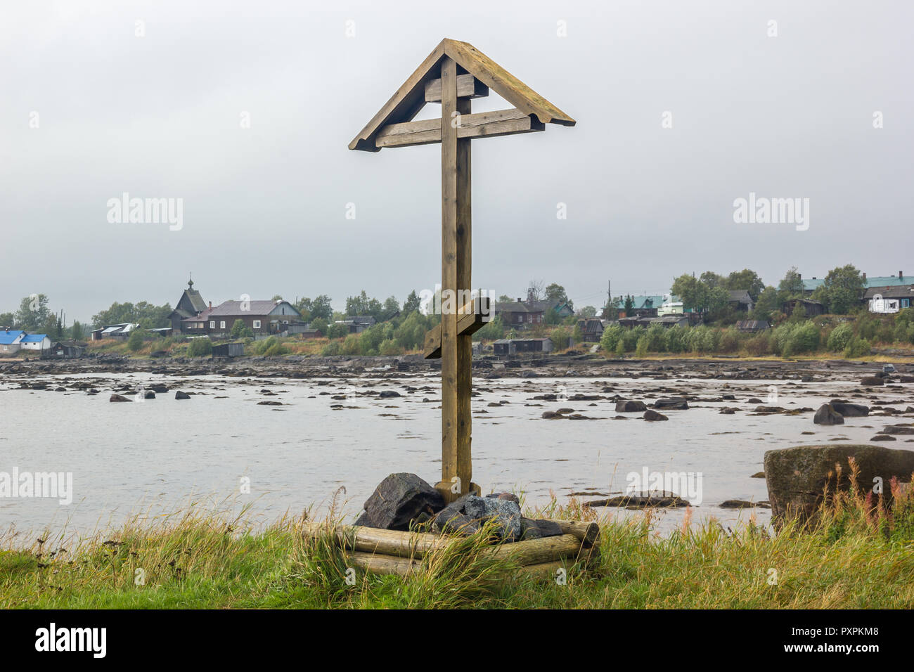 Orthodox Wooden Cross and Church with Houses on Background at Low Tide Stock Photo
