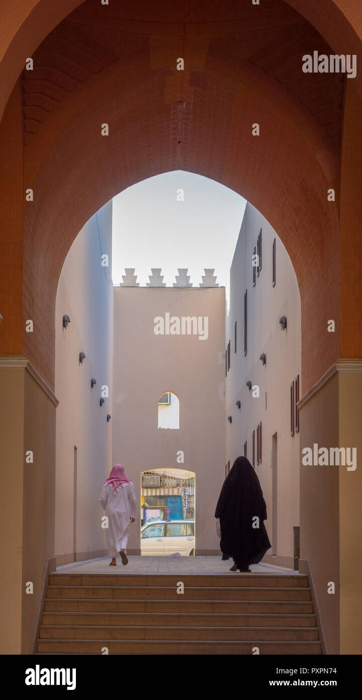 Unidentified man and woman walk toward the exit of a archway in Medina,  Saudi Arabia. Stock Photo