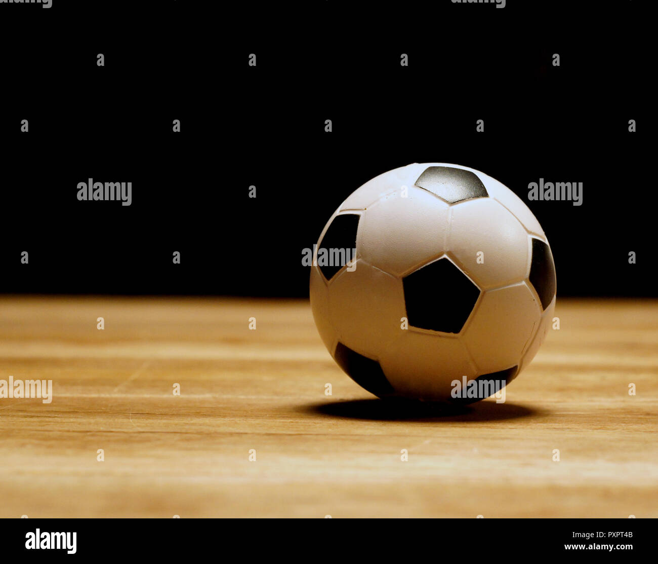 white and black mini football at wooden table Stock Photo