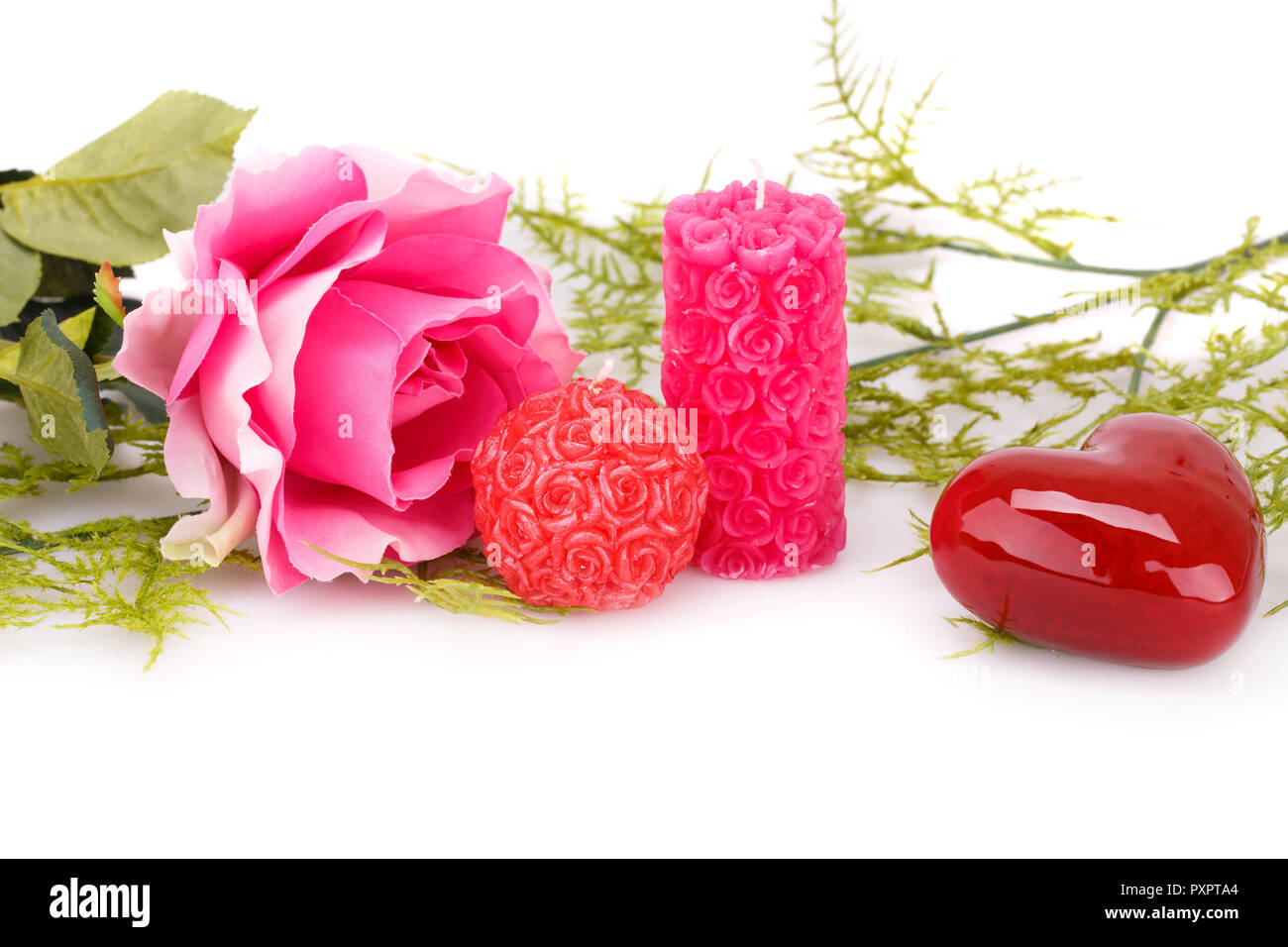 Candles, pink rose, glass heart and leaves isolated on white background ...