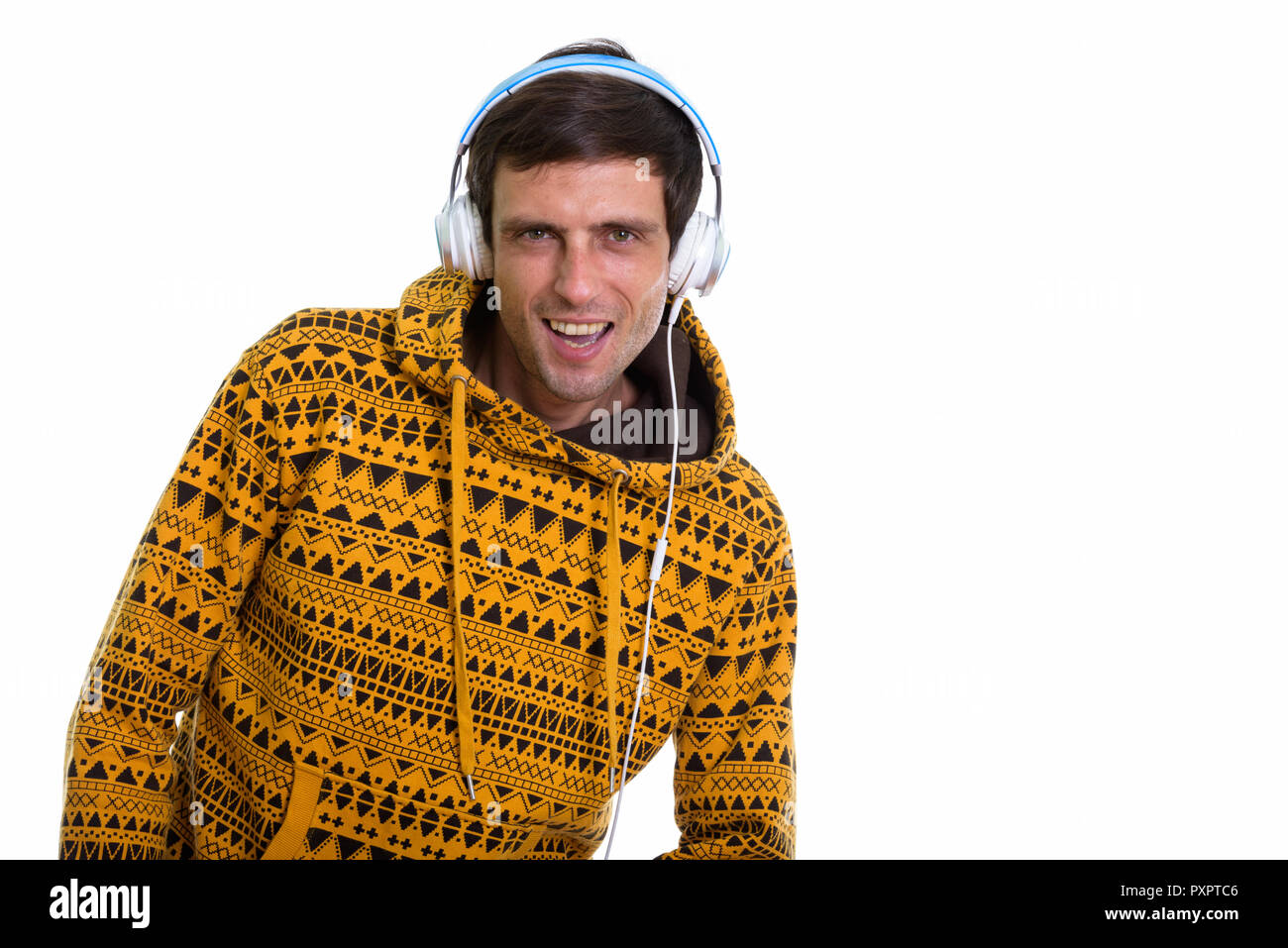 Studio shot of young happy man smiling while listening to music Stock Photo
