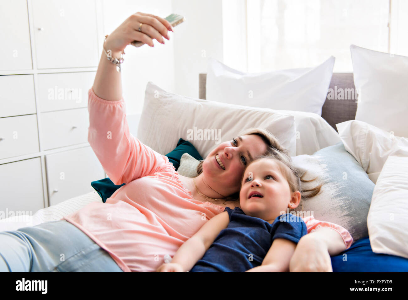 woman and children taking selfie with smartphone on bed Stock Photo
