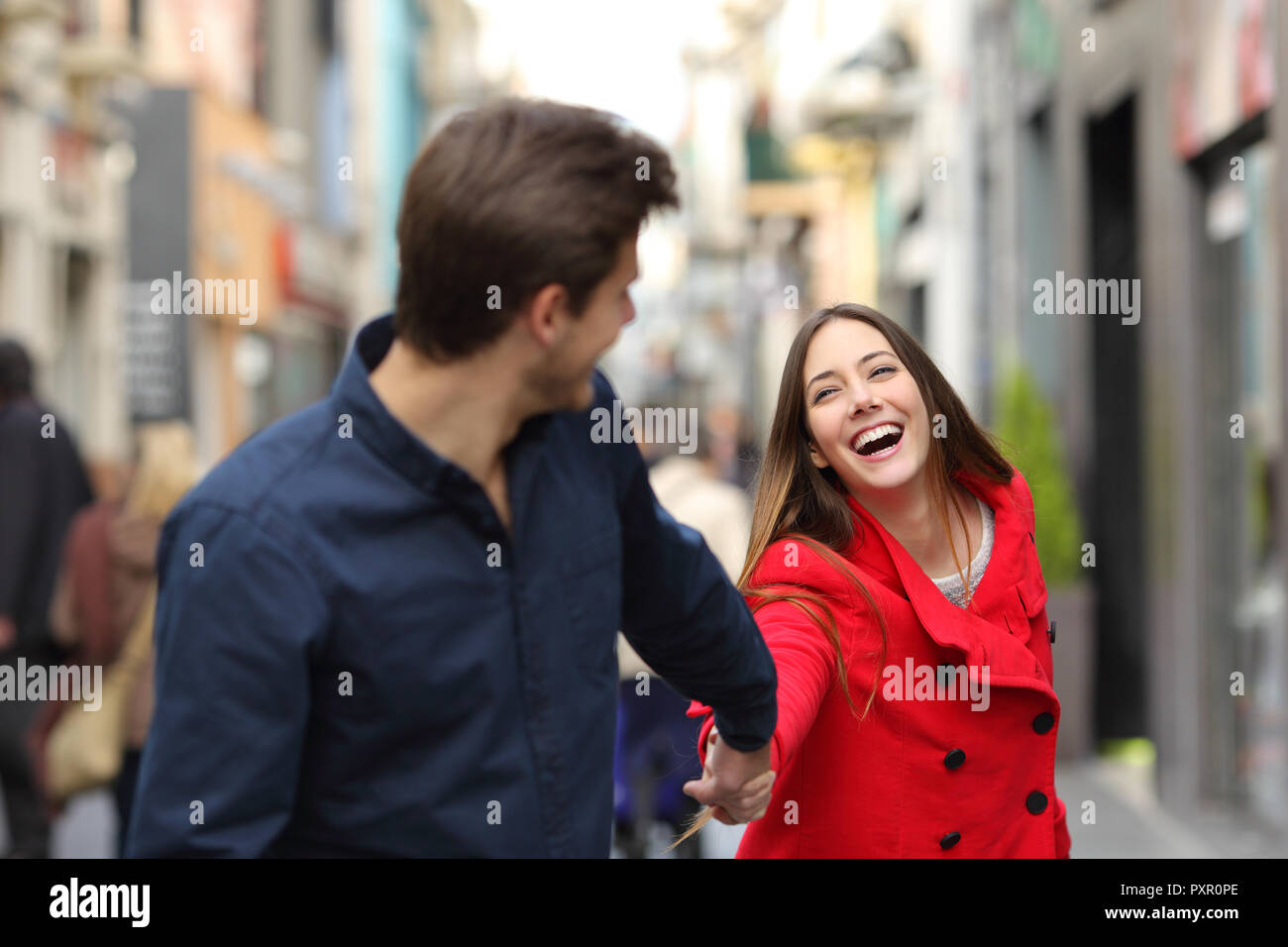 Happy couple running together in the street in winter Stock Photo