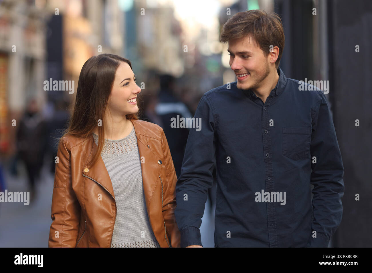 Front view portrait of a happy couple walking and talking in the street Stock Photo