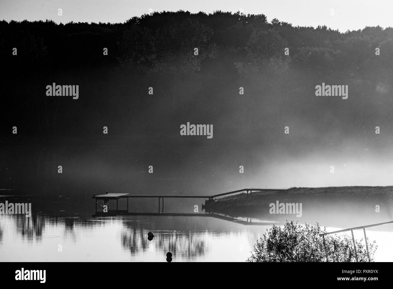 the pier on the lake. sunset, fog on the lake Stock Photo