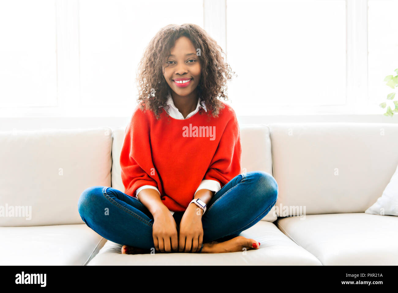 Attractive black young woman relaxing on a sofa at home Stock Photo - Alamy