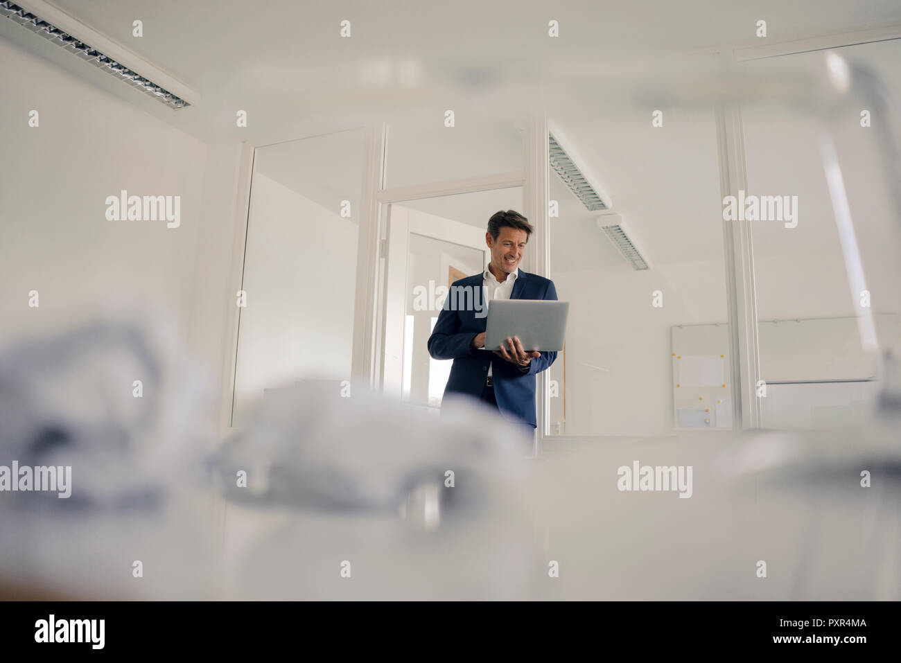 Businessman standing in office, using laptop Stock Photo