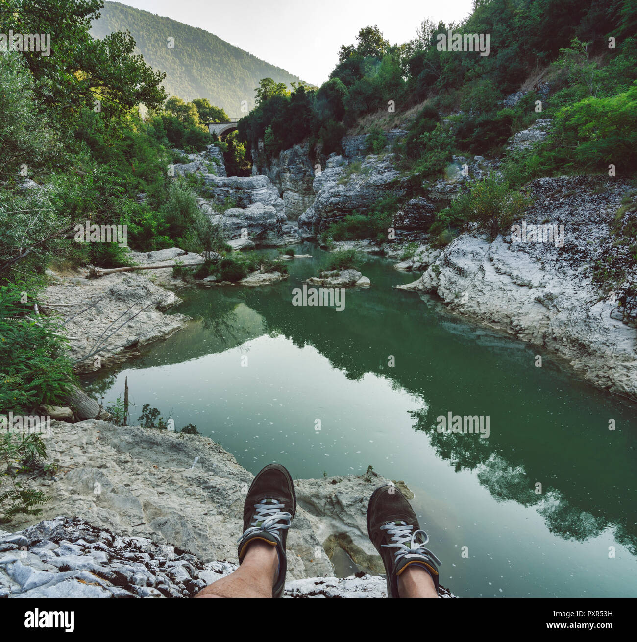 Italy, Marche, Fossombrone, Marmitte dei Giganti canyon, Metauro river, hiker sitting on riverside, shoes Stock Photo