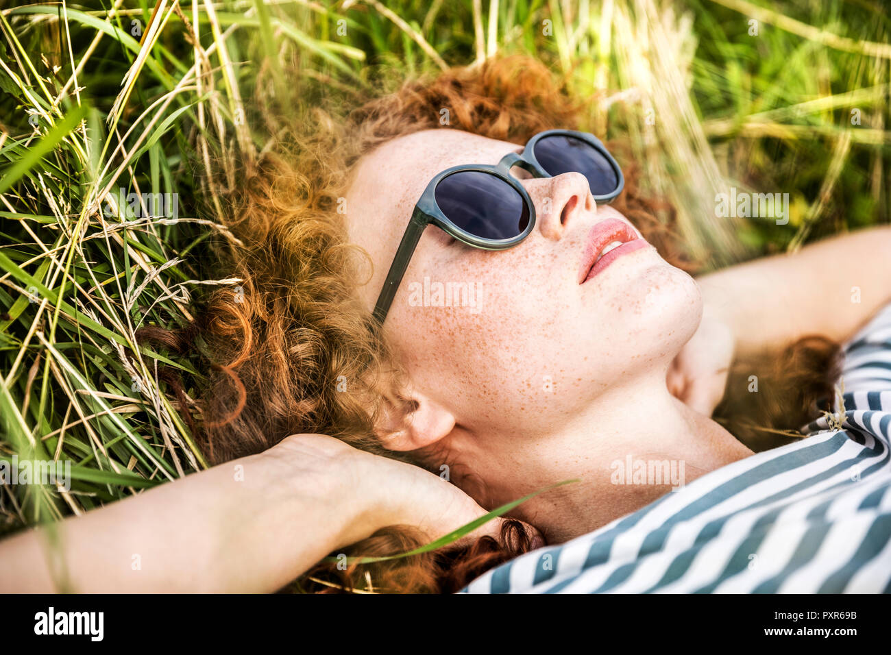 Young woman wearing sunglasses relaxing on a meadow Stock Photo