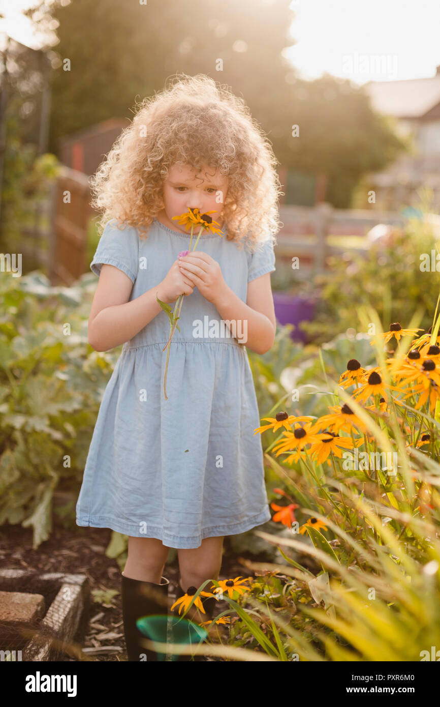 Little girl smelling flowers in the garden Stock Photo