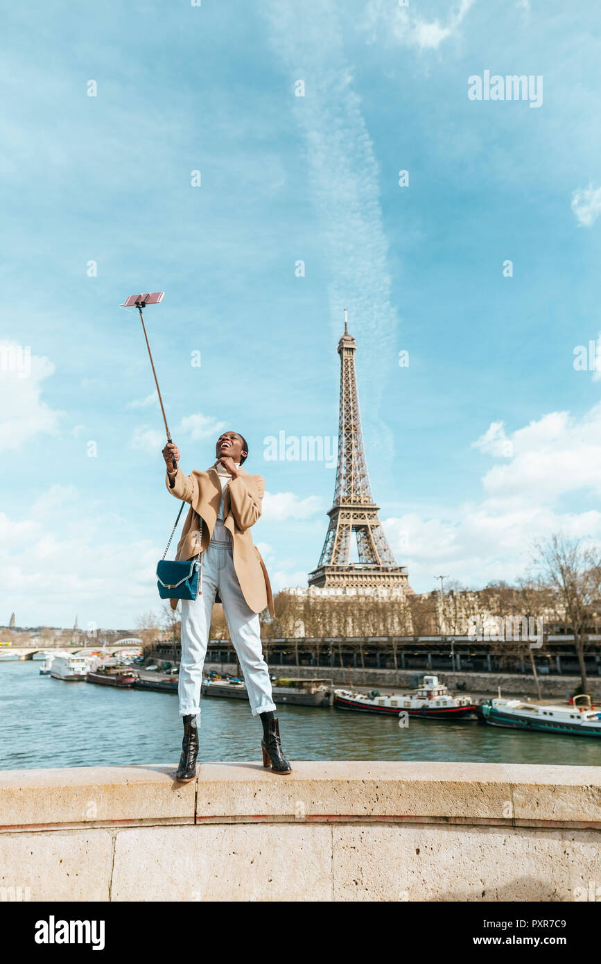 France, Paris, Woman standing on bridge over the river Seine with the Eiffel tower in the background taking a selfie Stock Photo