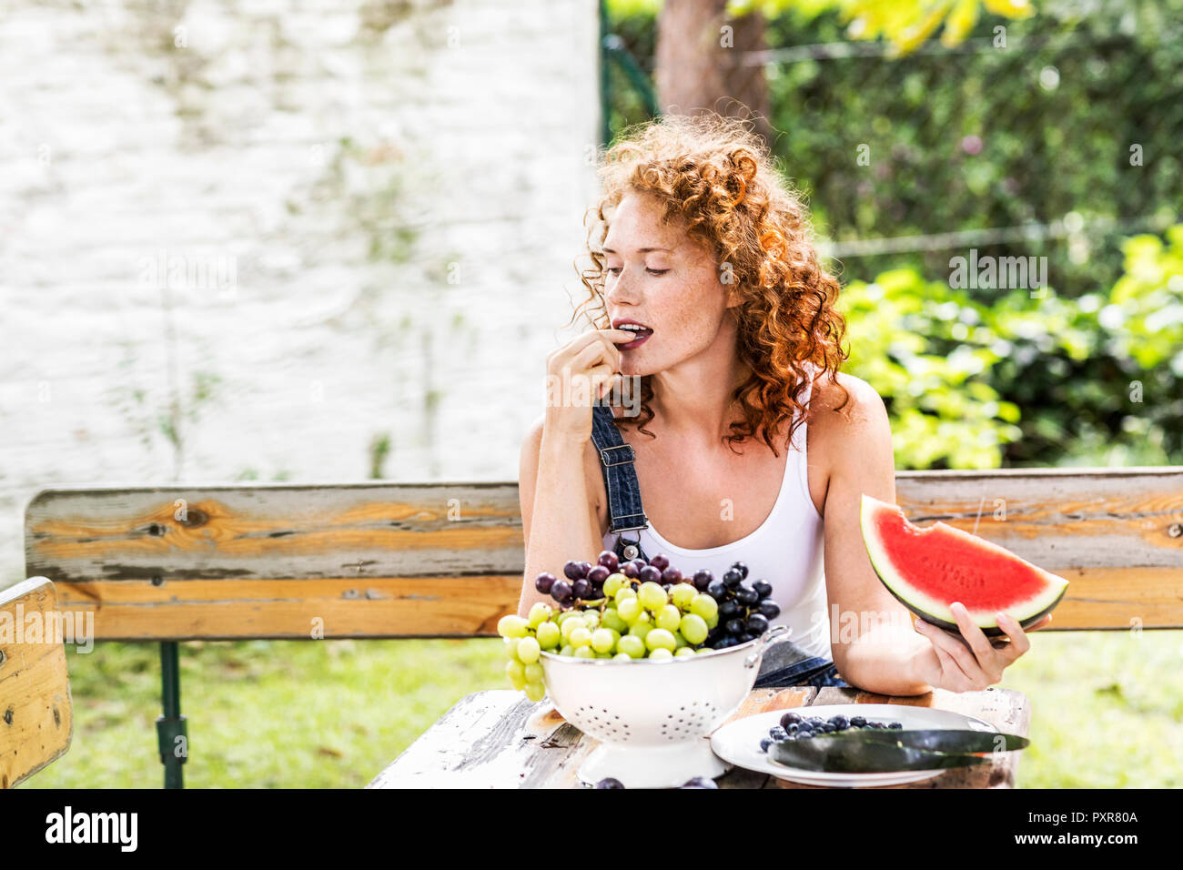 Redheaded young woman eating grapes in summer Stock Photo