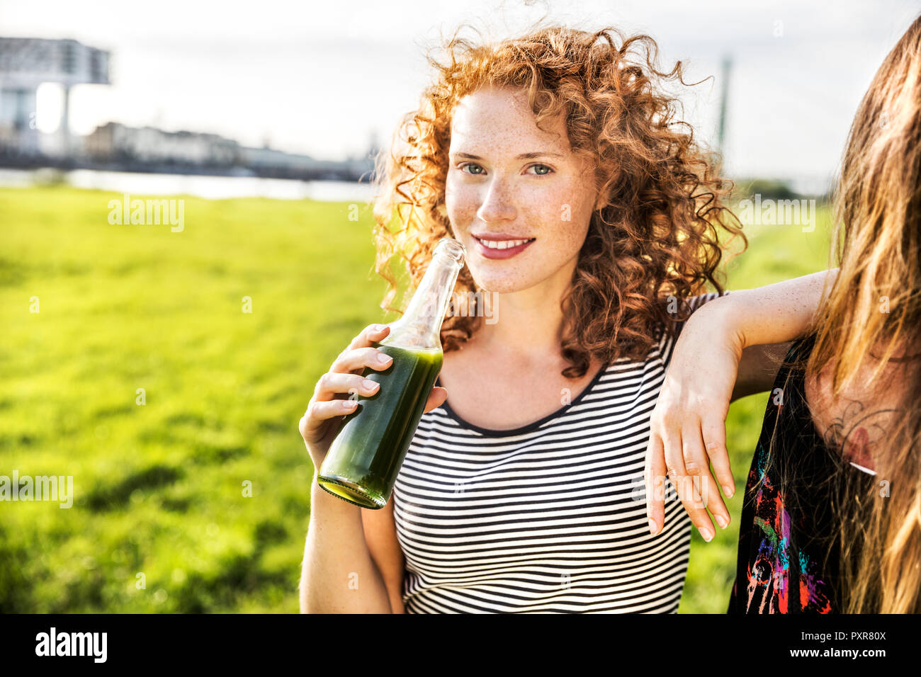 Germany, Cologne, portrait of redheaded young woman enjoying beverage Stock Photo