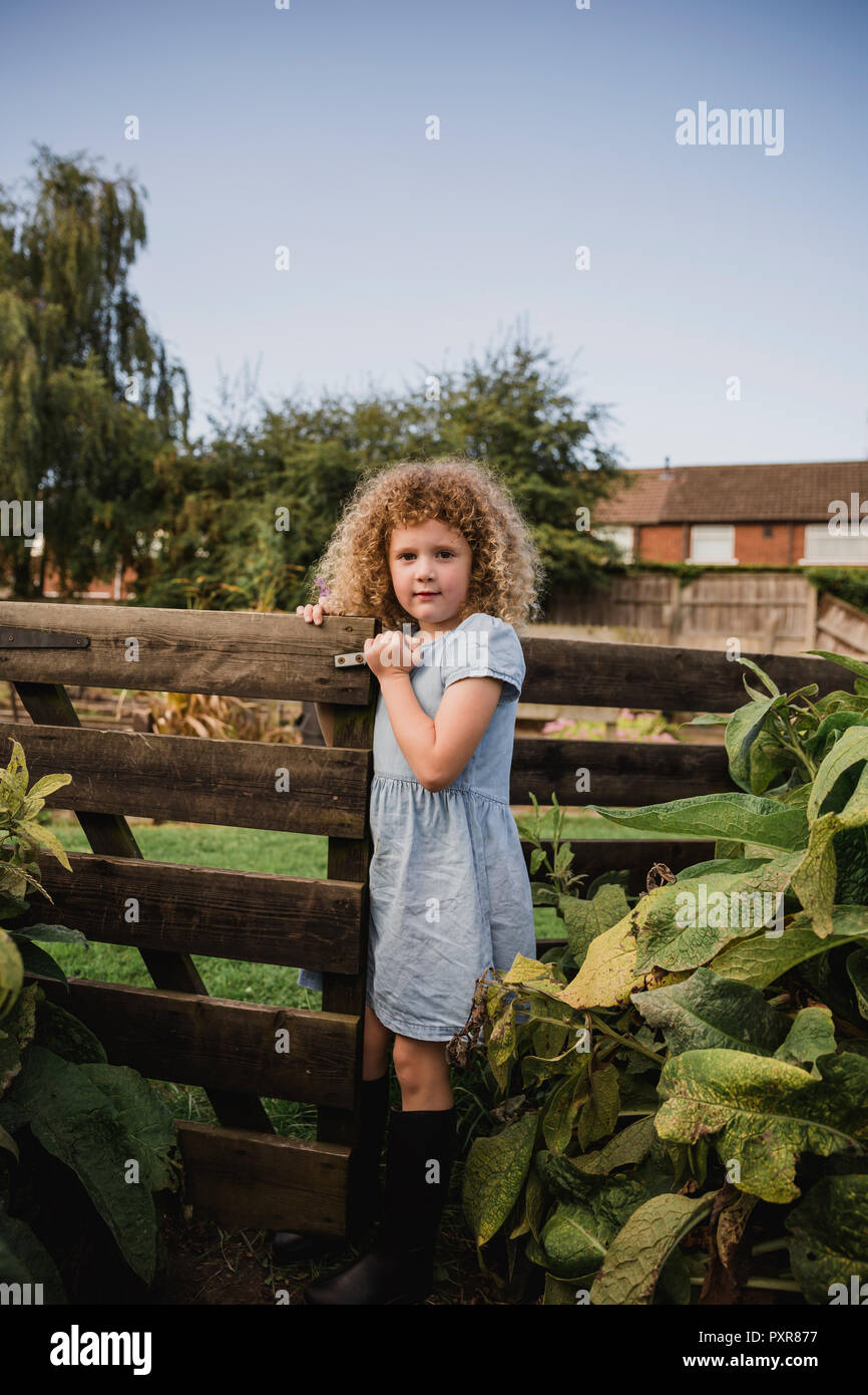 Portrait of little girl opening gate in the garden Stock Photo
