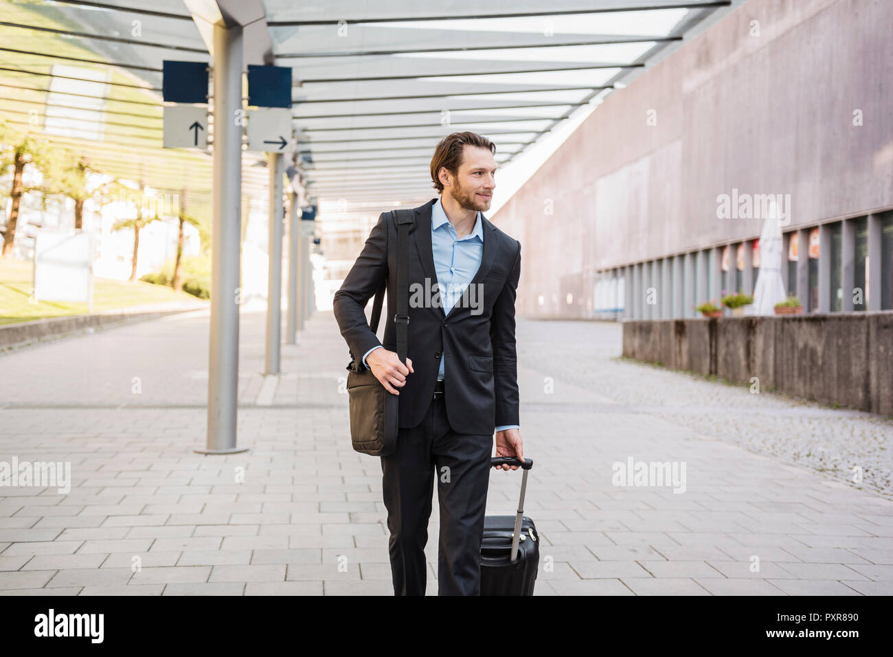 Businessman on the move pushing rolling suitcase Stock Photo