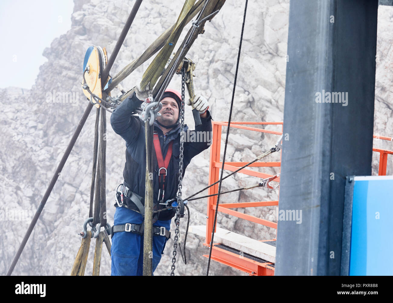 Germany, Bavaria, Garmisch-Partenkirchen, Zugspitze, installer working with rope pulley on goods cable lift Stock Photo