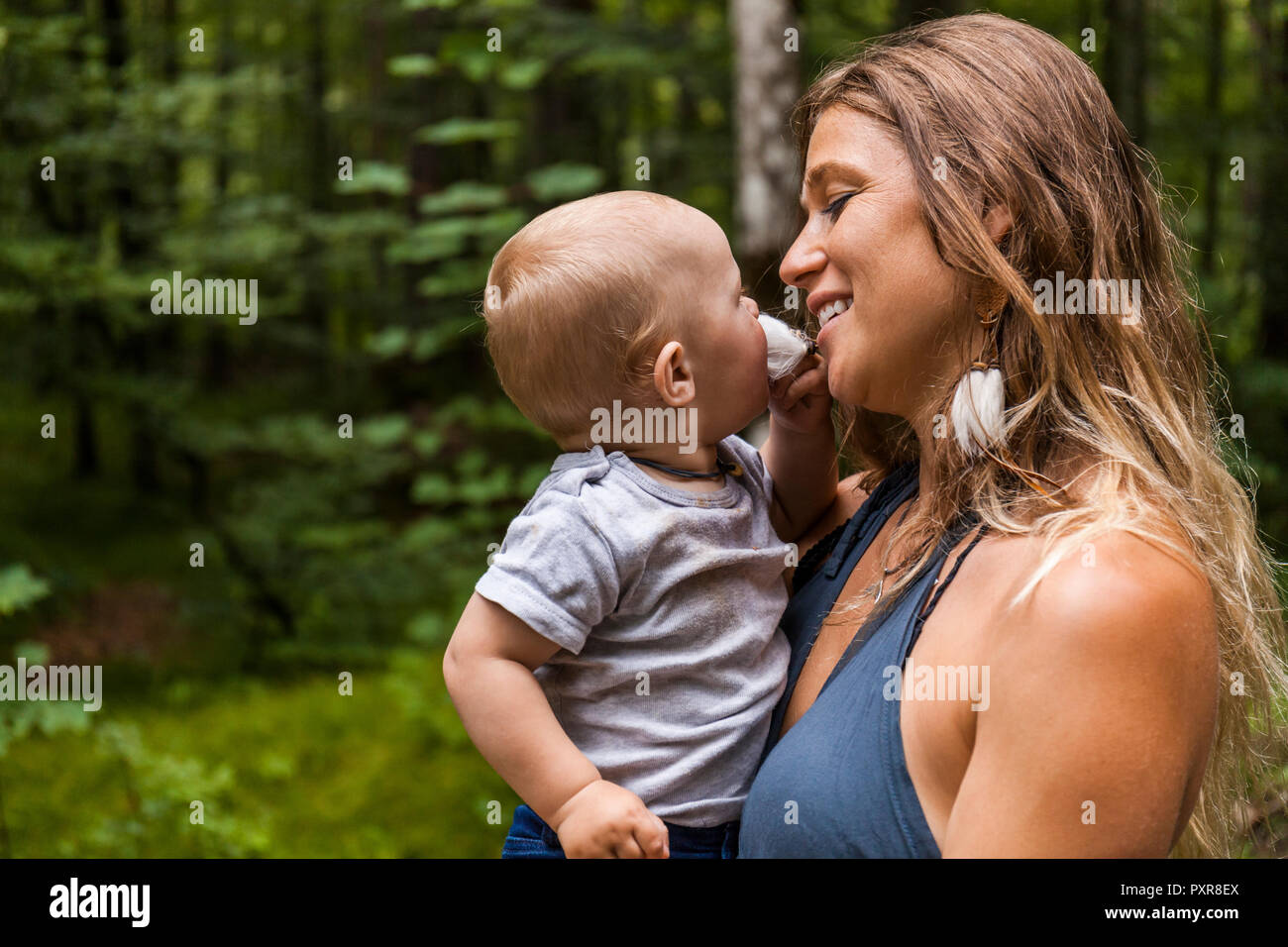 Smiling mother holding baby boy in forest Stock Photo