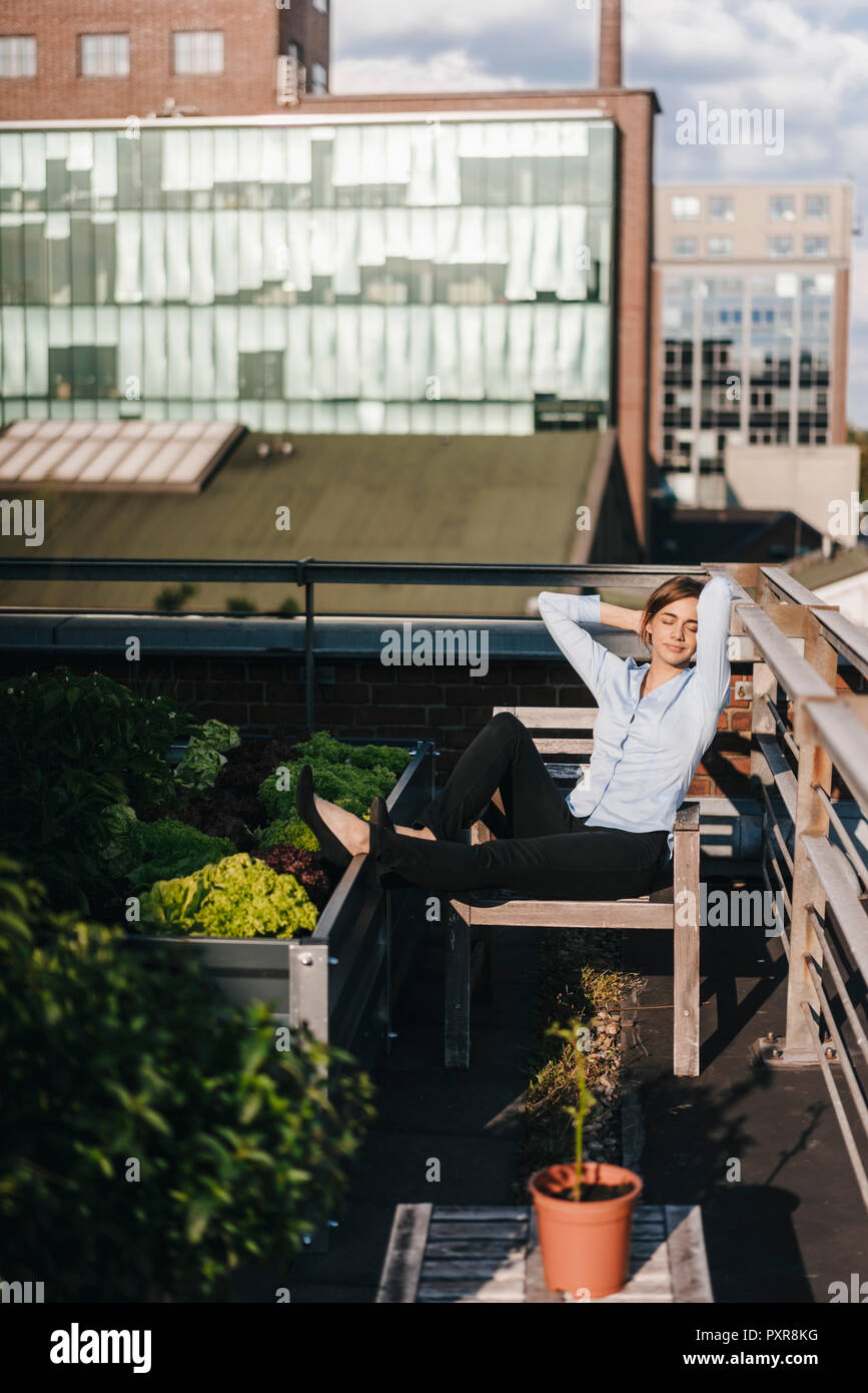 Businesswoman relaxing in his urban rooftop garden Stock Photo