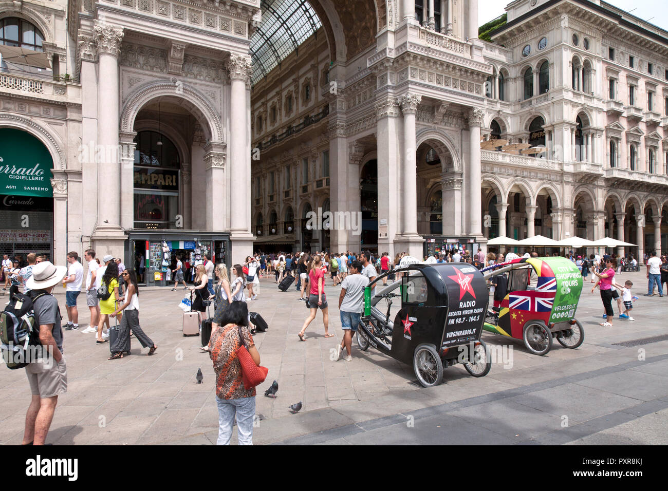 Crowd of people on the Piazza Duomo at its conjunction with Galleria Vittorio Emanuelle II. Note pedicabs. Stock Photo