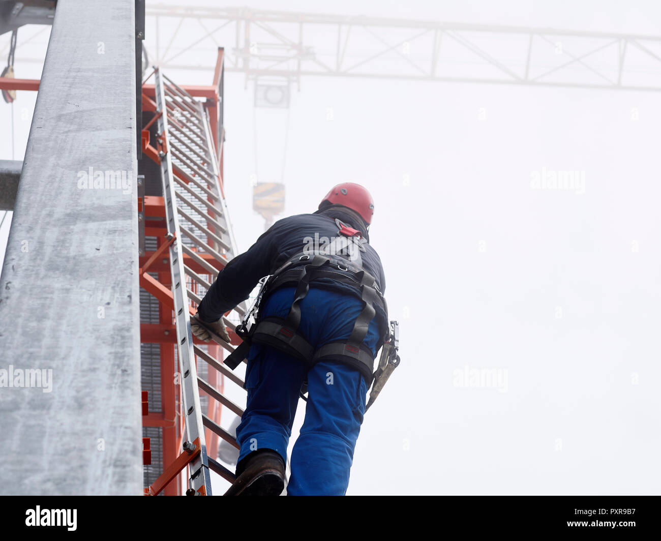 Germany, Bavaria, Garmisch-Partenkirchen, Zugspitze, installer climbing ladder on pole at goods cable lift Stock Photo