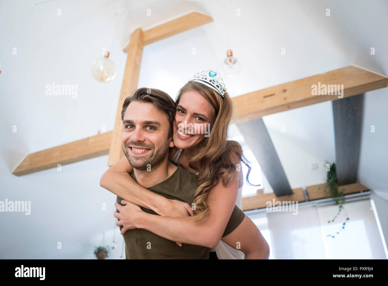 Portrait of happy couple at home with woman wearing tiara Stock Photo