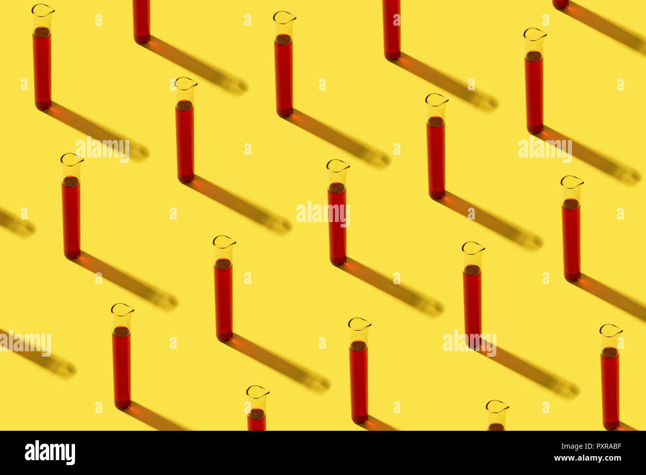 Row of test tubes with red liquid, yellow background Stock Photo