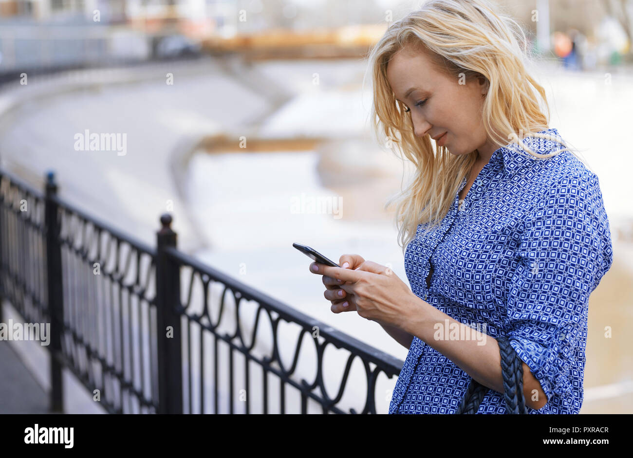 Blond woman using smartphone on a street Stock Photo