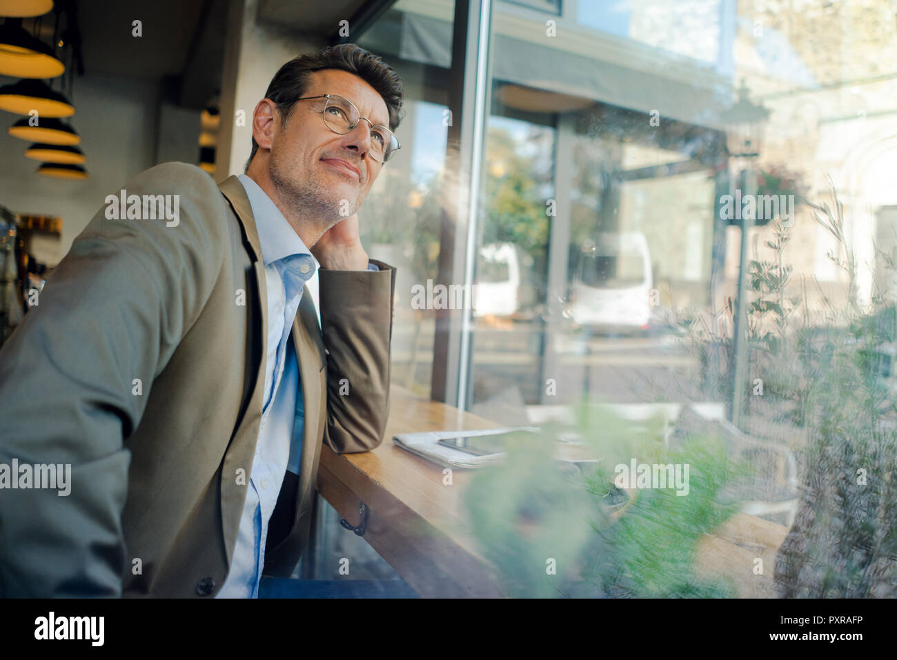 Mature businessman sitting in coffee shop, looking out of window Stock Photo