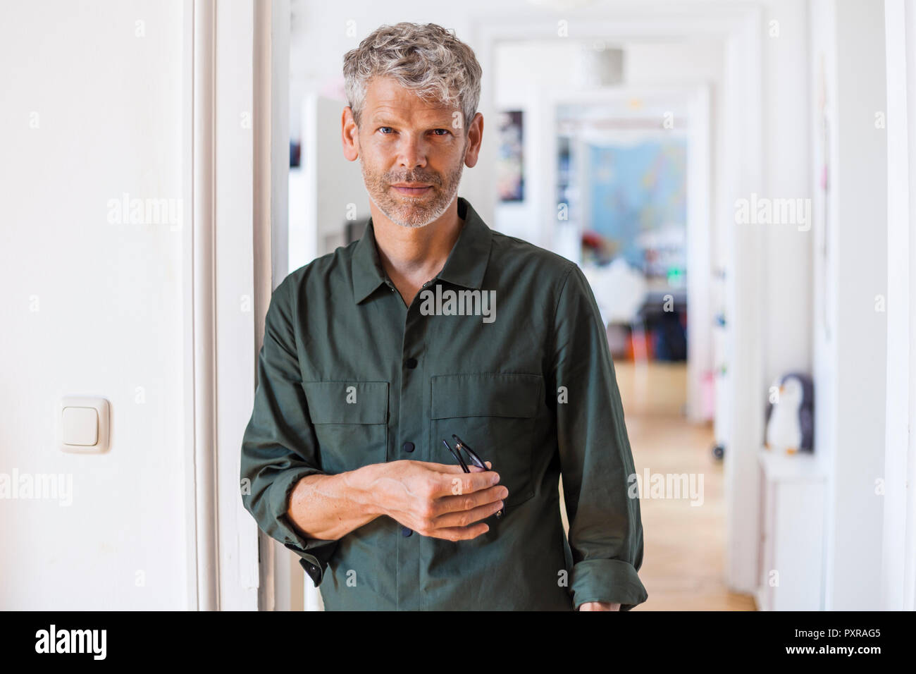 Portrait of mature man with grey hair and stubble at home Stock Photo