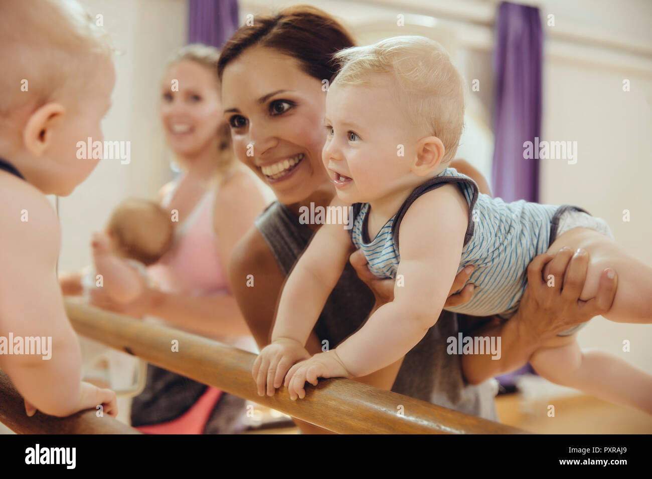 Mother holding up her baby to barre in dance studio Stock Photo