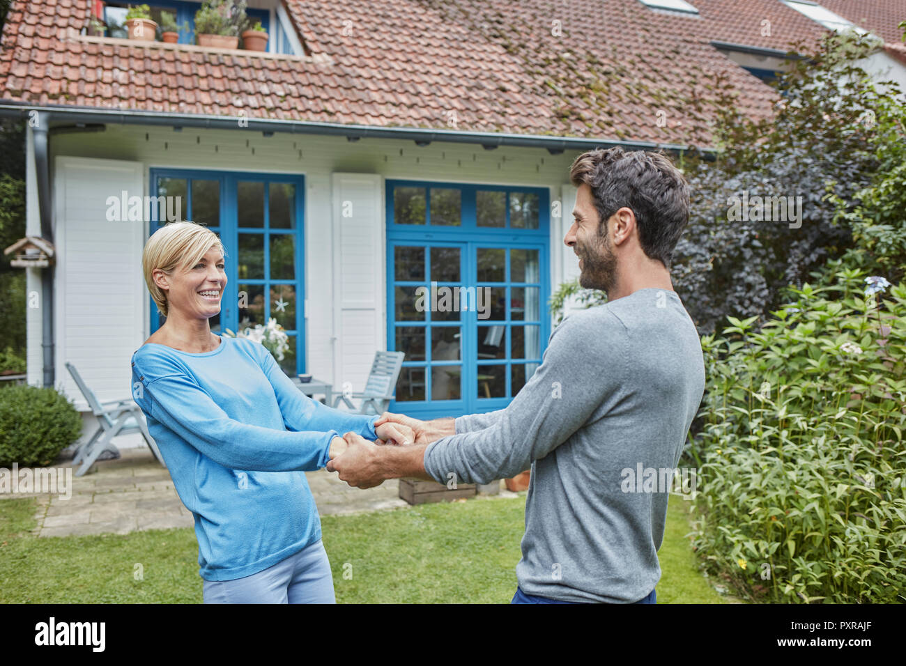 Happy couple dancing in front of their home Stock Photo