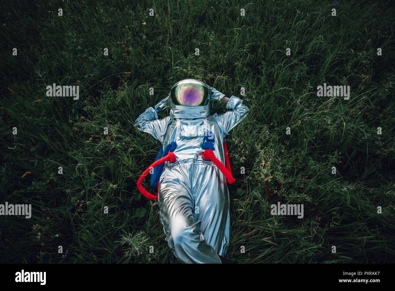 Spaceman exploring nature, relaxing in meadow Stock Photo