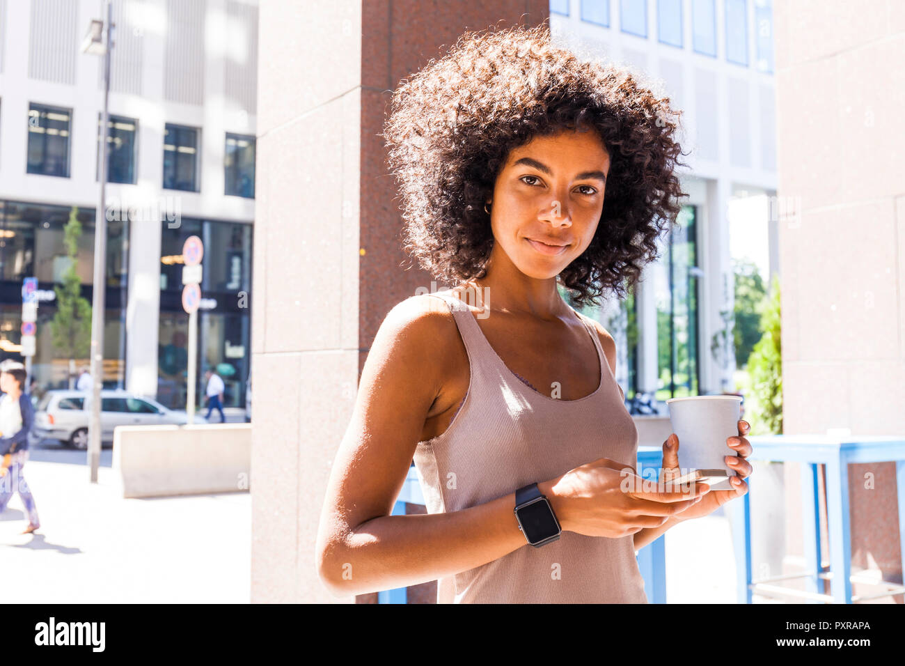 Portrait of smiling young woman with coffee to go and cell phone Stock Photo