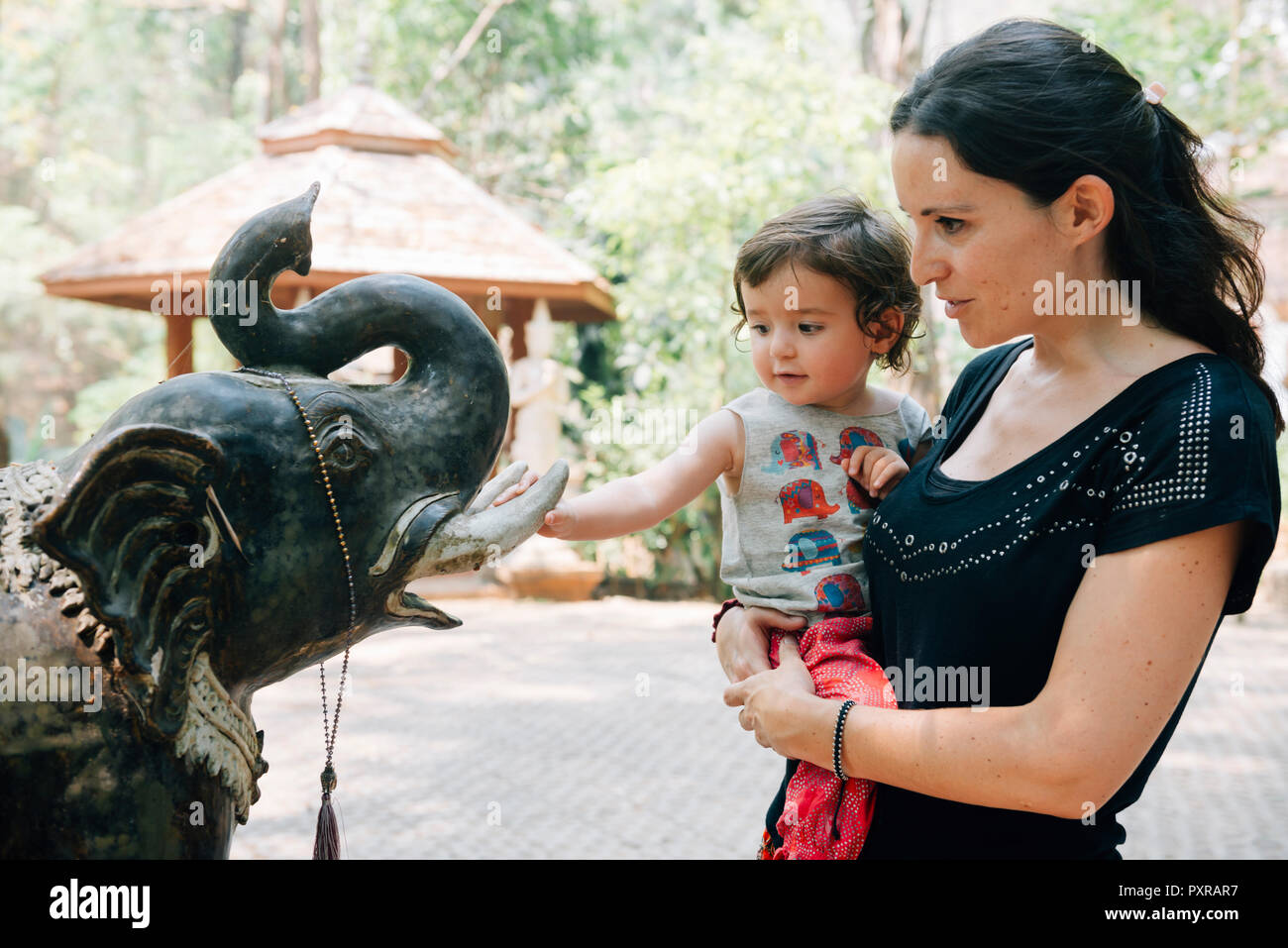 Thailand, Chiang Mai, Woman and child admiring the statue of an elephant at the Wat Pha Lat Buddhist temple Stock Photo