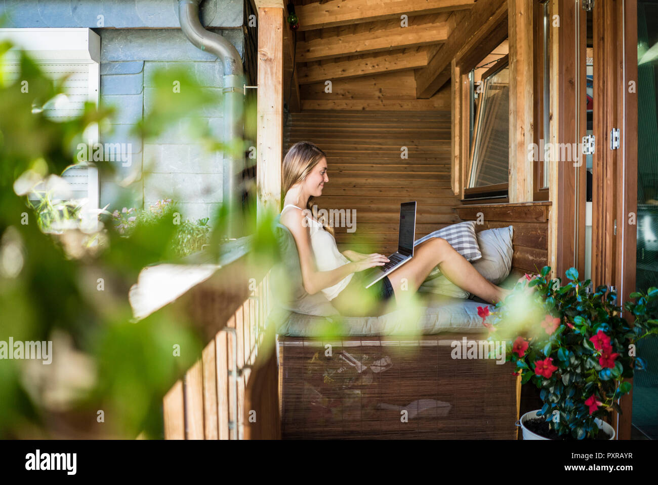 Smiling woman on balcony using laptop Stock Photo