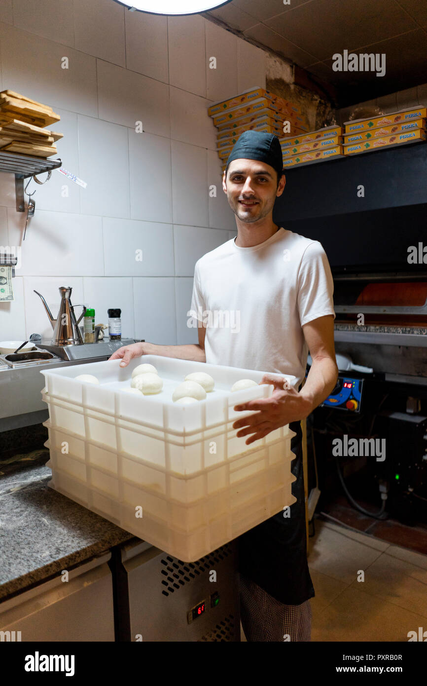 Portrait of smiling pizza baker with boxes of dough in kitchen Stock Photo