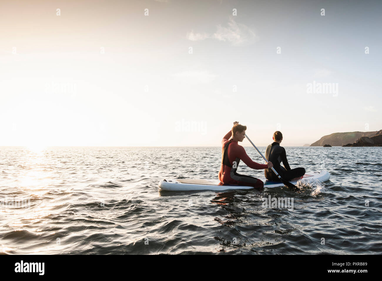 Couple on paddling on paddleboard at sunset on the sea Stock Photo