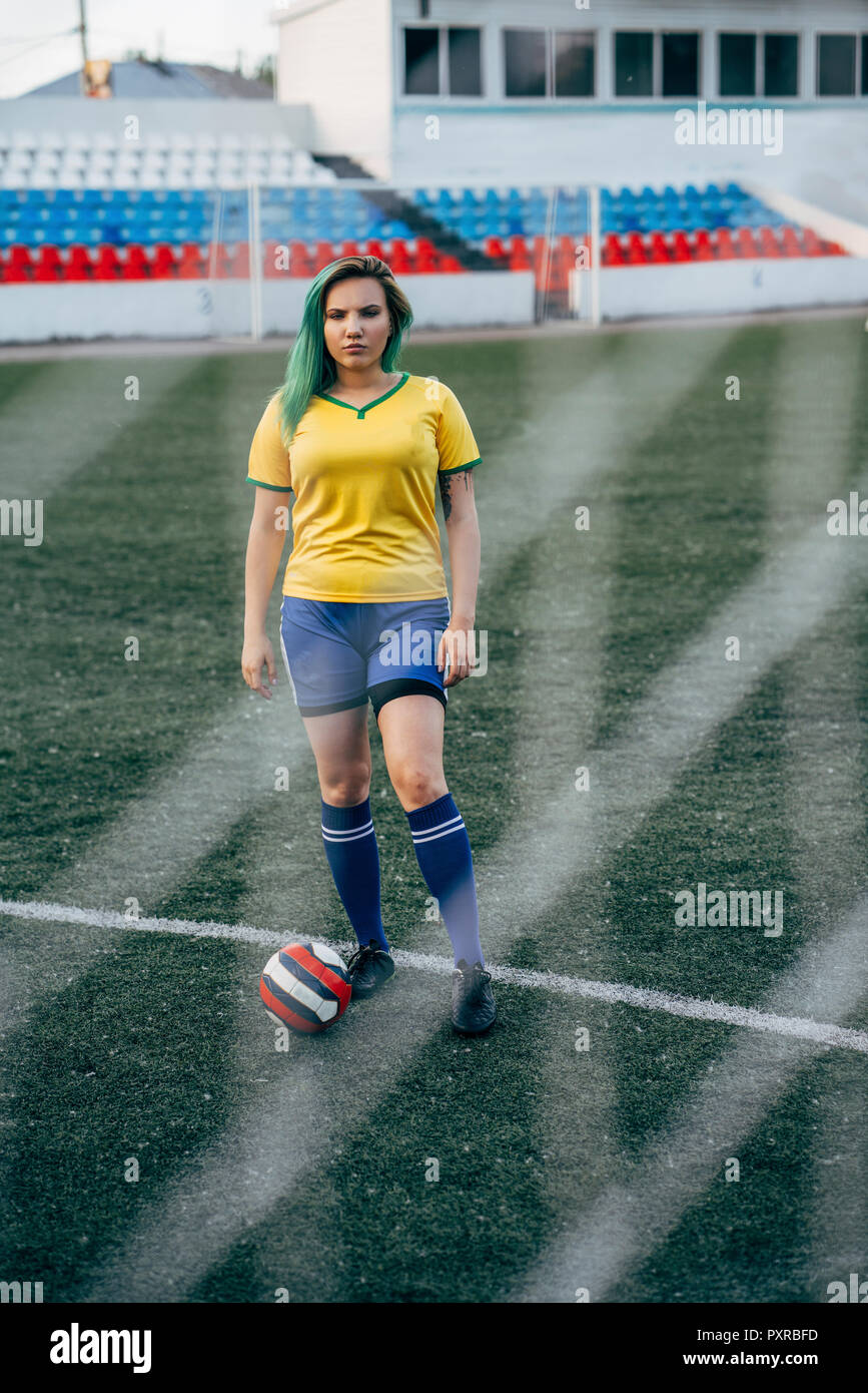 Young woman standing on football ground with the ball Stock Photo