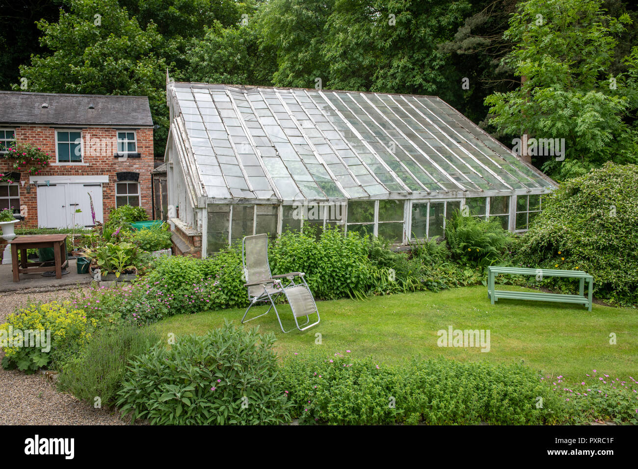 A greenhouse sits surrounded by nature and a brick house in Yorkshire