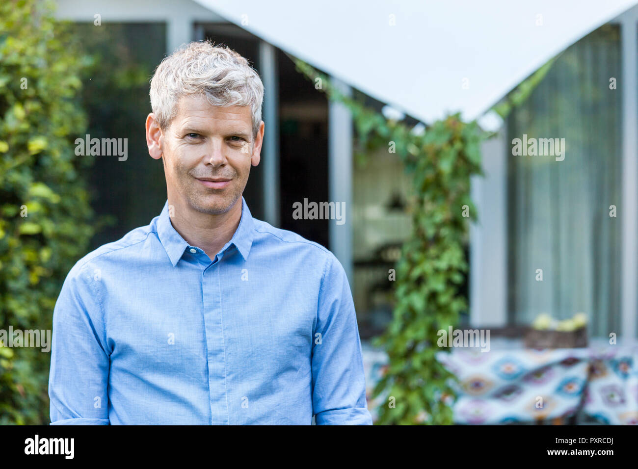 Portrait of content mature man with grey hair in front of his house Stock Photo