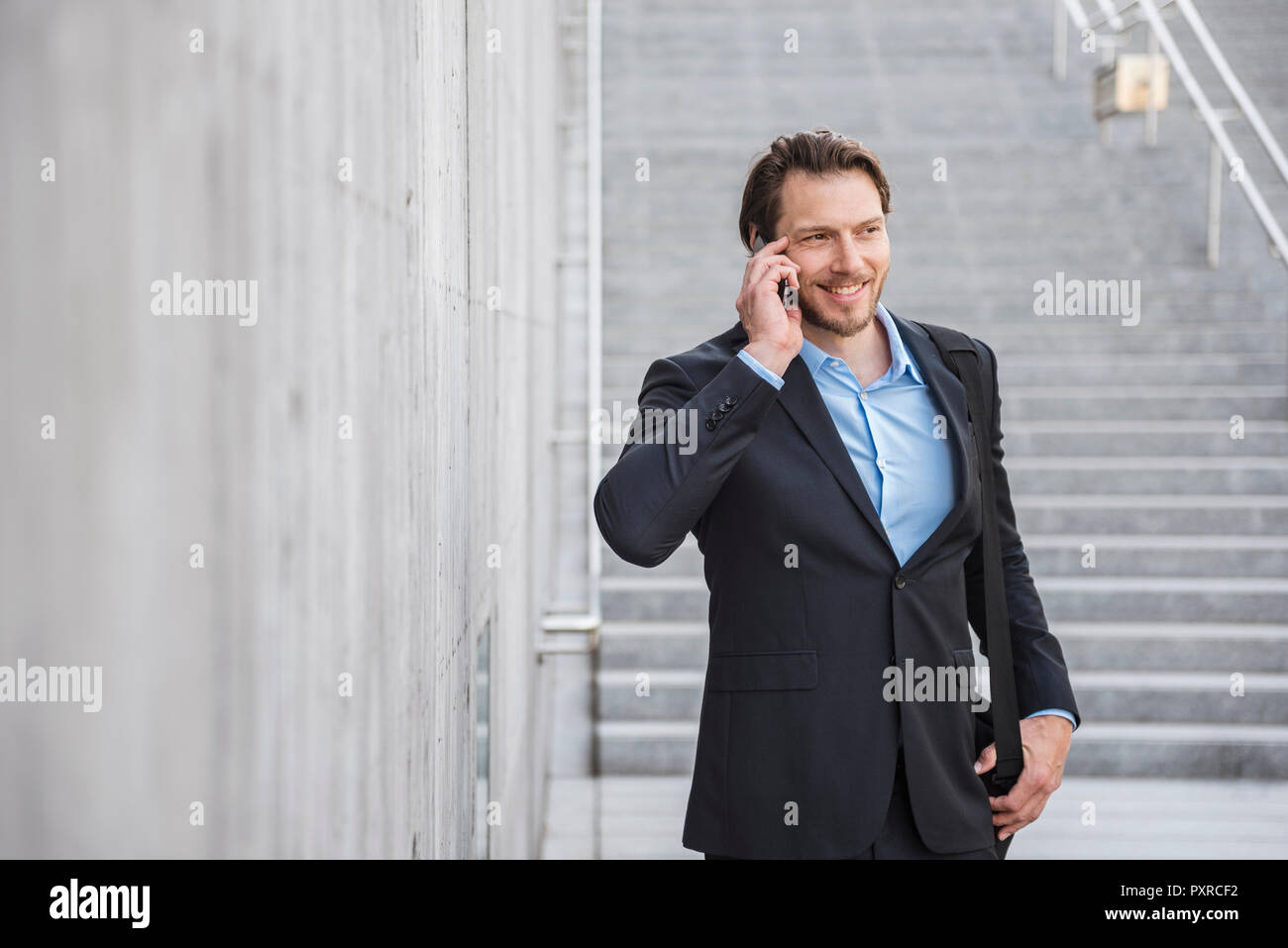 Smiling businessman at stairs talking on smartphone Stock Photo