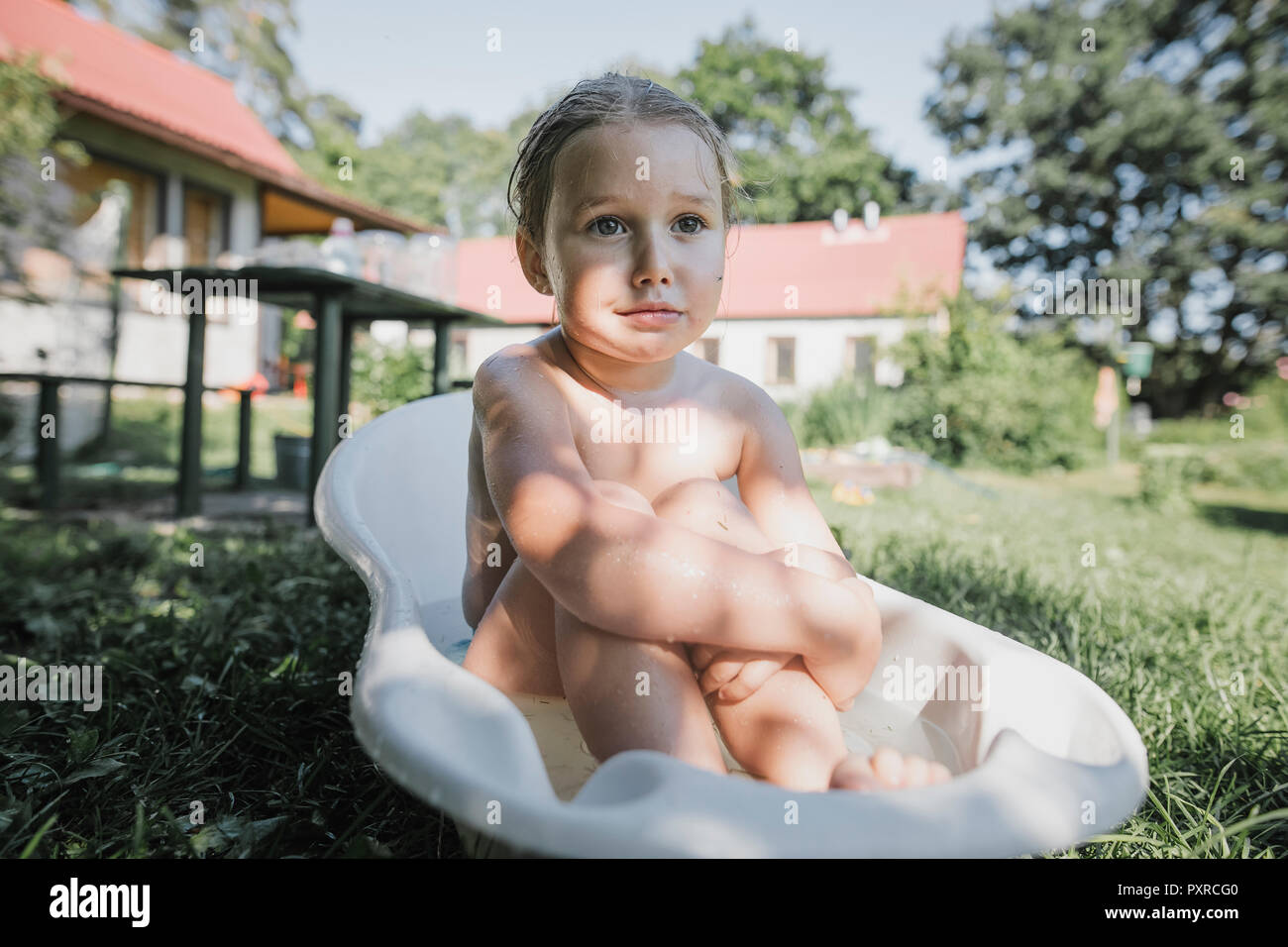 Portrait Of Little Girl Sitting In Bath Tub In Garden Stock