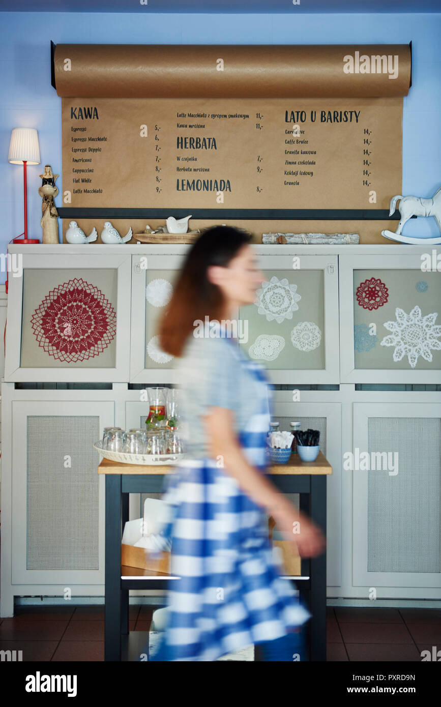Waitress walking past drinks menu in a cafe Stock Photo