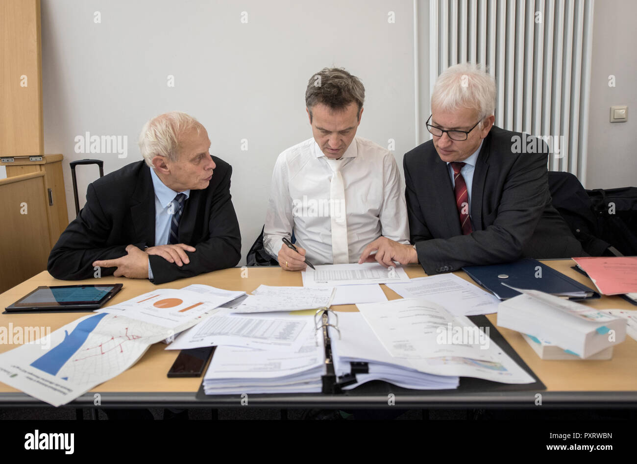 24 October 2018, Rhineland-Palatinate, Mainz: Axel Friedrich (l-r), consultant for the managing directors of Deutsche Umwelthilfe (DUH), Remo Klinger, specialist lawyer for administrative law, and Jürgen Resch, managing director of Deutsche Umwelthilfe (DUH), are sitting in the courtroom before the start of negotiations. The court is negotiating a possible ban on diesel driving in the state capital of Rhineland-Palatinate. The case concerns a complaint by Deutsche Umwelthilfe (DUH) against the city of Mainz concerning exceeded limit values for nitrogen dioxide (NO2) in the air. Photo: Andreas  Stock Photo