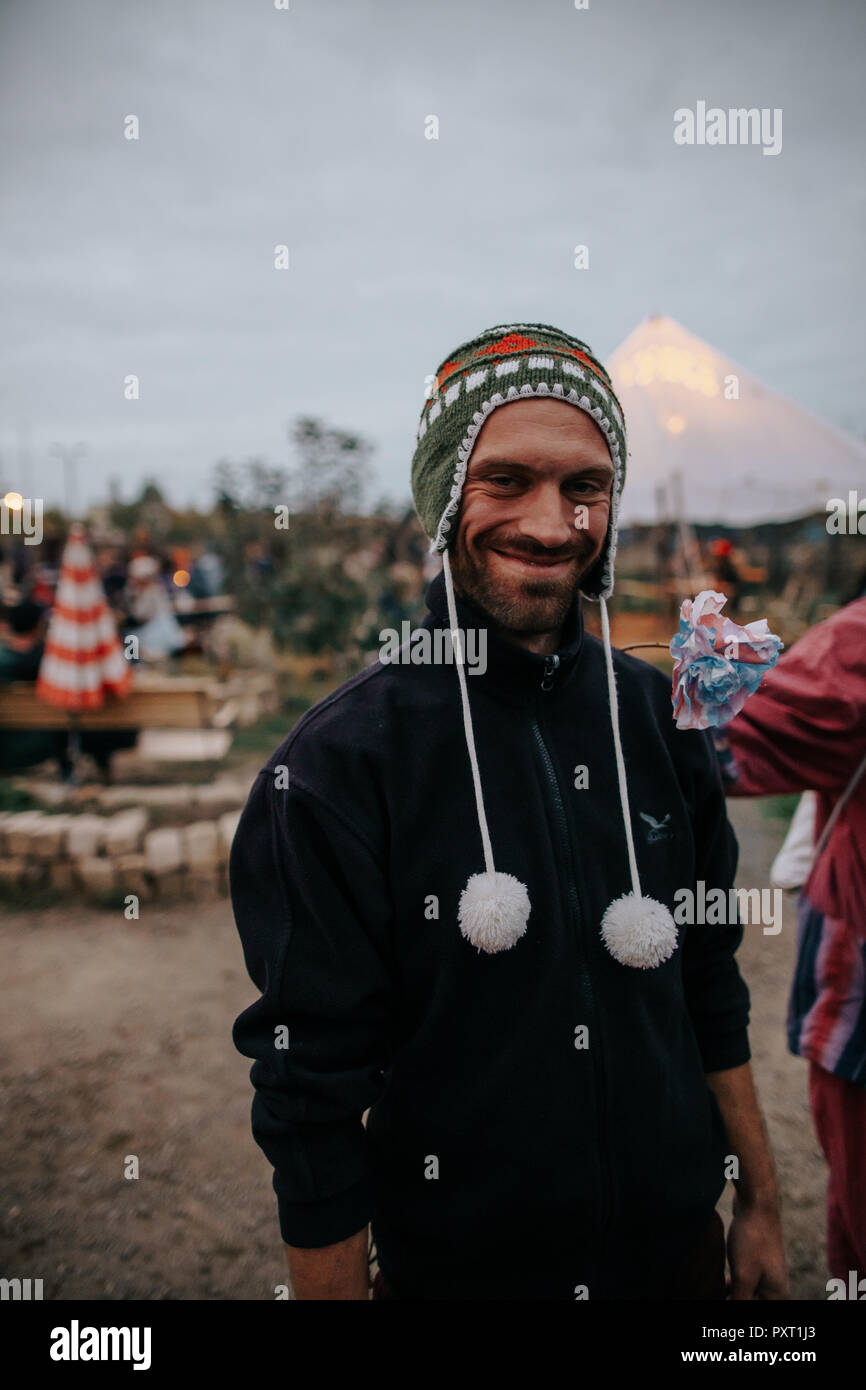 Photo of smiling man who is wearing a peruvian wool cap to keep warm at a outdoors music festival Stock Photo