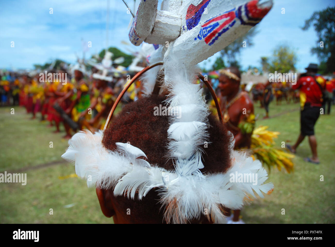 Colourfully dressed and face painted men with boat hat designs dancing as part of a Sing Sing in Madang, Papua New Guinea. Stock Photo