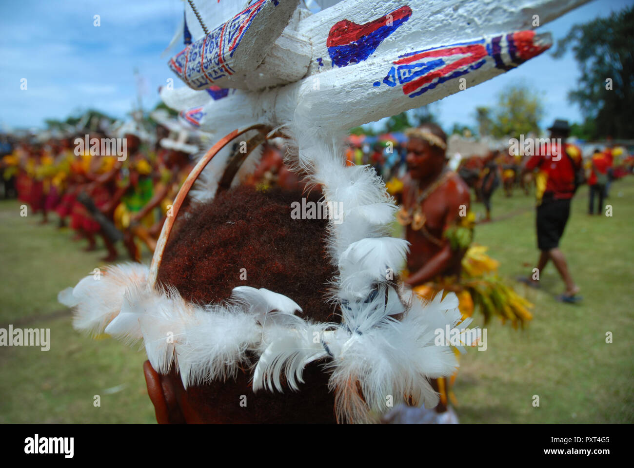 Colourfully dressed and face painted men with boat hat designs dancing as part of a Sing Sing in Madang, Papua New Guinea. Stock Photo