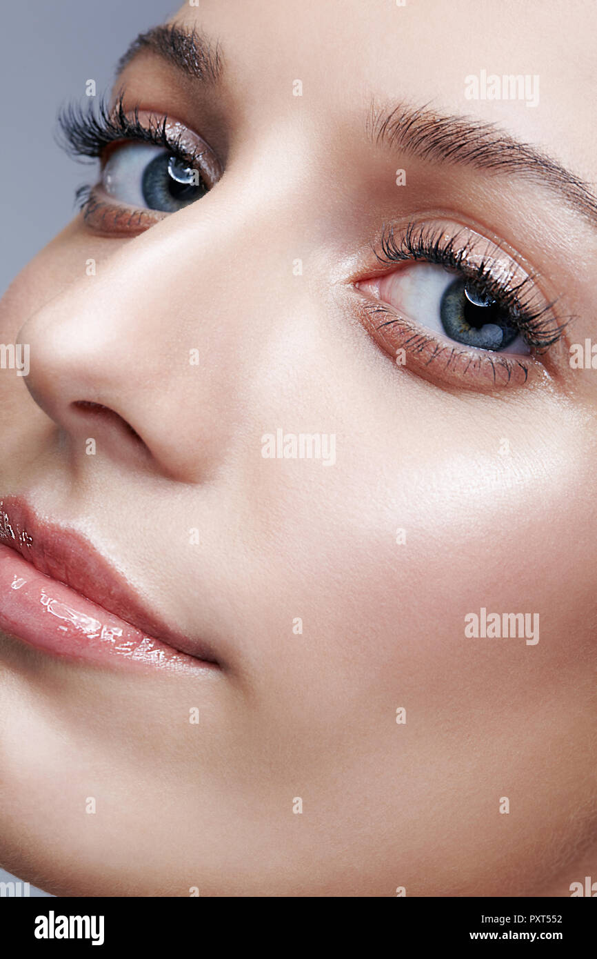 Closeup macro shot of female face and eyes beauty makeup. Woman with glossy glitter white skin. Stock Photo